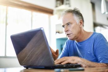 Claiming Social Security Early? Don't Get Caught Off-Guard by This Rule.: https://g.foolcdn.com/editorial/images/756086/retired-man-computer-screen-investing-stocks-paying-bills.jpg