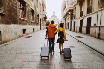 Why Expedia Stock Was Up 11.5% in December: https://g.foolcdn.com/editorial/images/760275/two-people-walk-a-paved-city-street-towing-luggage.jpg